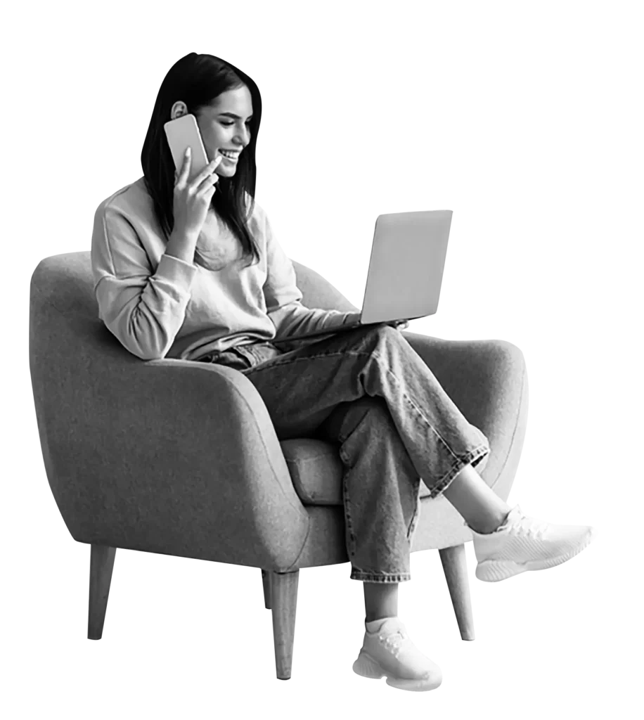 Young woman multitasking on laptop and phone on a comfy sofa